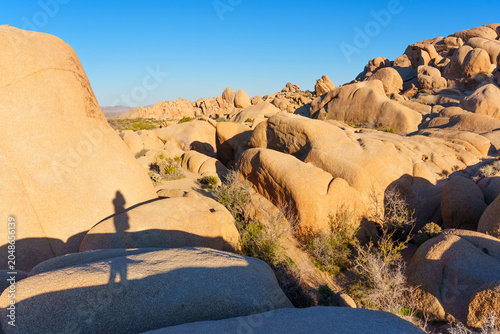 Hiker Shadow Cast on Giant Granite Rock Formations in Joshua Tree Park
