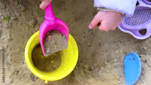 Watch the enchantment unfold in this adorable video. A child's hands skillfully fill a bucket with sand, illustrating the simple joys of playtime that awaken endless imagination.