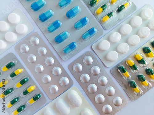 Foto Medical pills, tablets, capsules in various colors and shapes inside blister packs, arranged on white background, for healthcare, drugs, medications, dosage, pharmacy, medicine packaging concepts