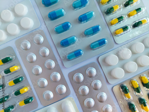 Slika na platnu Medical pills, tablets, capsules in various colors and shapes inside blister packs, arranged on white background, for healthcare, drugs, medications, dosage, pharmacy, medicine packaging concepts