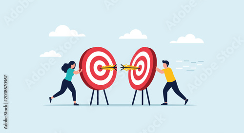 Two people work together to push two large targets with arrows in them toward each other representing merging goals and team alignment.