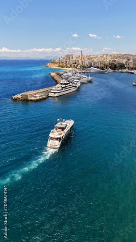 Aerial drone photo of small yacht cruising in low speed near marina and port of Zea or Pasalimani, Piraeus, Attica, Greece