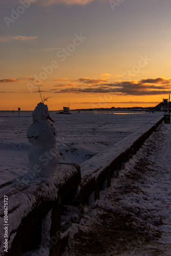 Quadro su tela Snow man on Snow-Covered Lowestoft Beach at Sunset, Suffolk Coast, England