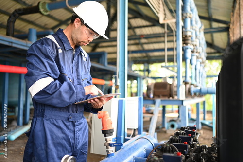 Industrial engineer inspecting pipeline systems and equipment inside a water treatment facility. Worker monitoring infrastructure, maintenance processes and utility operations for safe production.