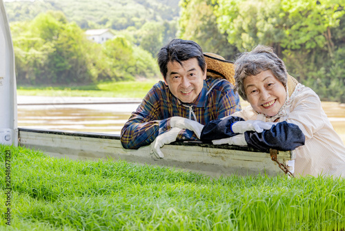 Foto 稲苗を積んだ軽トラックにもたれて微笑むシニア夫婦