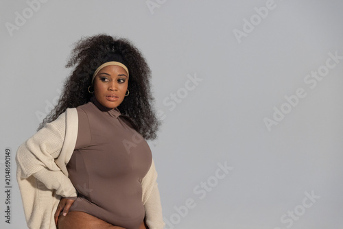 Картината върху платно African American woman posing in studio wearing brown high-neck bodysuit, cardig