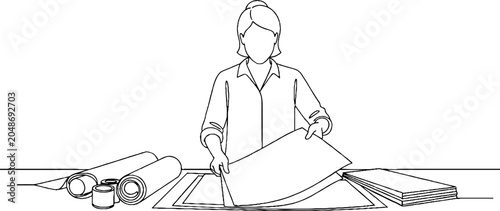 Architectural draftswoman reviewing large blueprints at workstation.