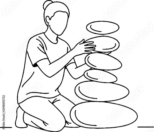 Person carefully balancing and stacking oval plates artistically.