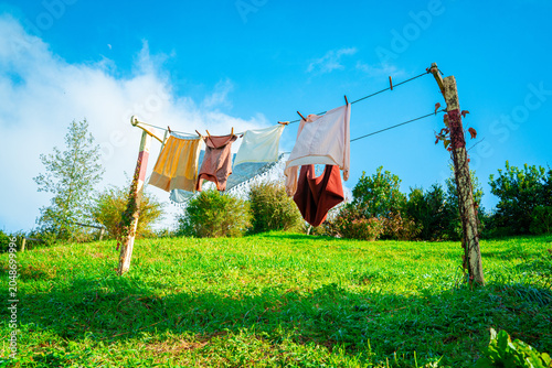 Εκτύπωση καμβά Clothes drying rack and colourful clothes on the green grassy slope