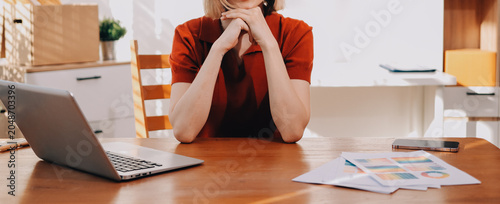 Young woman works on a touchpad, feeling comfortable at cozy home office with a green plant on the background