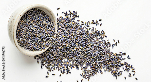 Pile of dried lavender buds scattered from a ceramic bowl