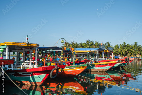 Obraz na plátně Colorful wooden tourist vessels docked on a calm river