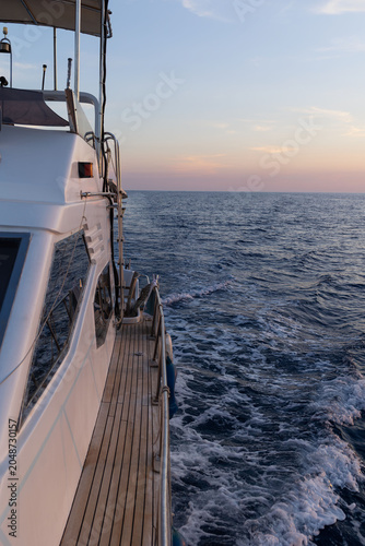 Billede på lærred View along the starboard side walkway of a motor yacht as it cruises on open water at sunset