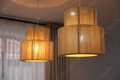 Fotografía Warm pendant lamps cast a soft ambient glow over a modern living room with sheer curtains, creating a cozy, elegant interior atmosphere ideal for evening relaxation and stylish home decor inspiration