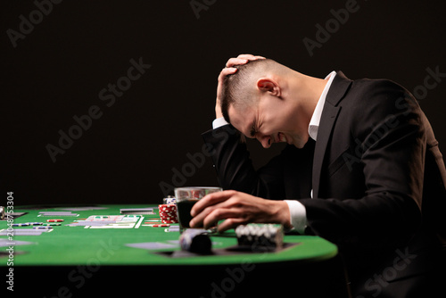 Young devastated businessman losing poker game at casino