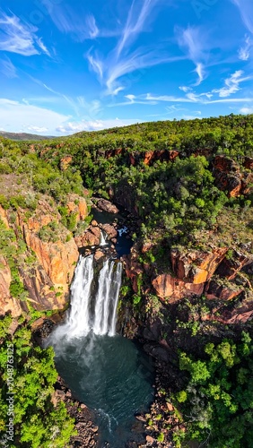 Majestic waterfall cascading through autumn forest valley.