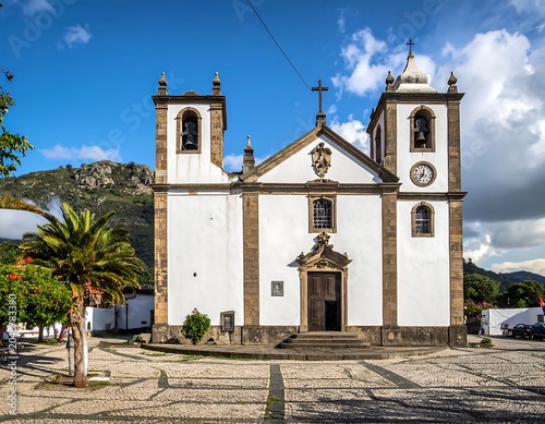 Historic white church with clock tower on sunny day.