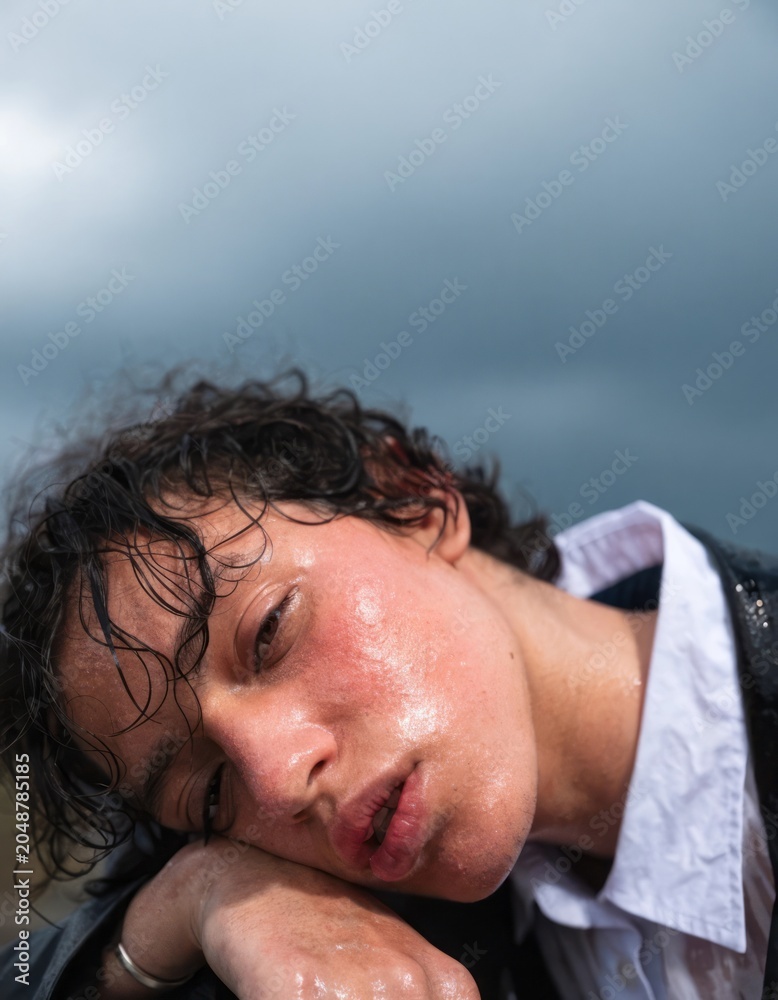 Fototapeta premium Young Person with Wavy Hair Posing Under Cloudy Sky in Rainy Weather with Dramatic Expression