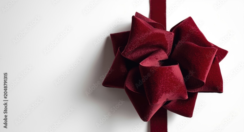 Obraz premium Luxurious burgundy velvet bow isolated on a plain white background for holiday gift wrapping