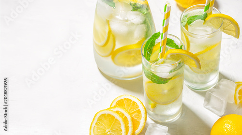 Fotografía Fresh homemade lemonade with lemon slices, mint and ice on white background, sum