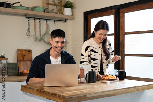 Billede på lærred Happy Asian Couple in Kitchen with Laptop and Breakfast, Smiling Together at Hom
