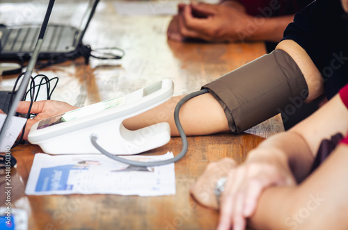 Annual checkup concept. Doctor is measuring patient's blood pressure. The patient has a blood pressure cuff on his arm.