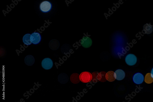 Abstract blurred background of colorful city street and traffic lights at night. Perfect for atmospheric nocturnal cityscapes, modern graphic design, or moody photo overlay effects.