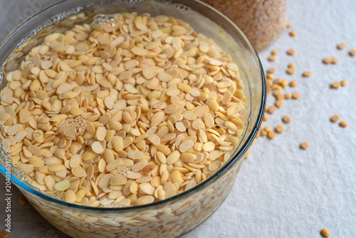 Bild auf Leinwand Yellow split soybeans soaking in water inside a glass bowl.