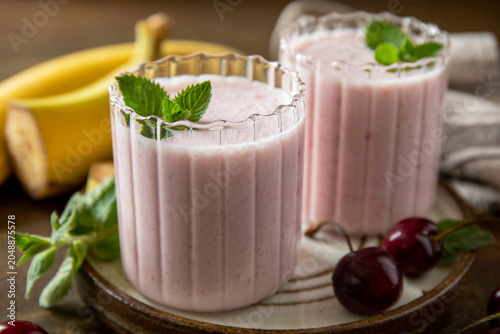 Close up pink cherries and banana fruit smoothie or milk protein shake on stone tabletop. Yogurt cocktail, natural detox. Liquid ice cream.