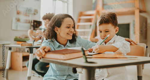 Foto A warm and encouraging scene of a Hispanic teacher guiding a young boy writing i