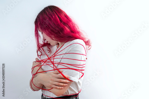 Photos Teenage girl with pink hair wrapped in red lines symbolizing imposed social rules, pressure and stereotypes, personal boundaries and conflict avoidance, fear of confrontation and self expression