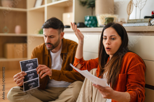 Obraz na płótnie Couple reacting to unexpected pregnancy ultrasound news with shock
