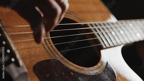 Close up of hands playing strings of acoustic guitar.