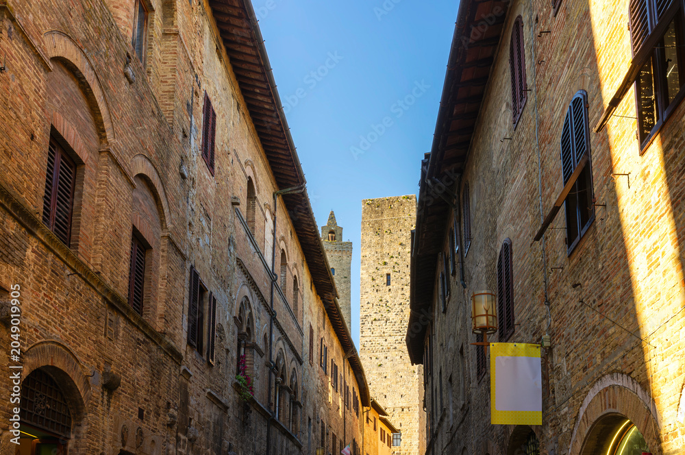 Naklejka premium View of and old alley in San Gimignano, medieval village of Tuscany (Province of Siena, Italy); is world famous for its renaissance monuments and white wine production (named 