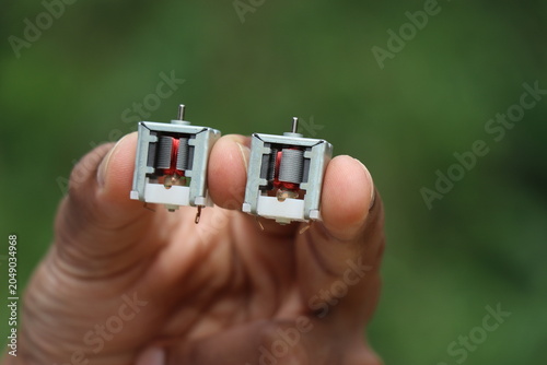 Obraz na plátně Micro DC motor or known as open frame dc motors held Between fingers with visibl
