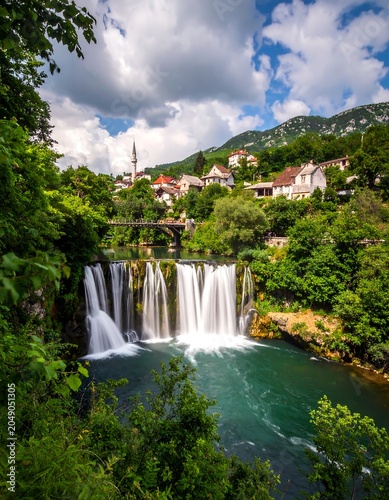 Scenic waterfall cascades with village and vibrant foliage