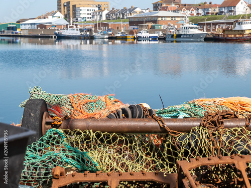 Fotografía Close up of commercial fishing nets and rusty trawling gear on the quayside in S