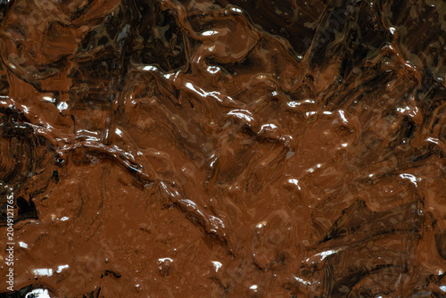Photos An abstract painting of mixed black and brown acrylic paint with a glossy textur