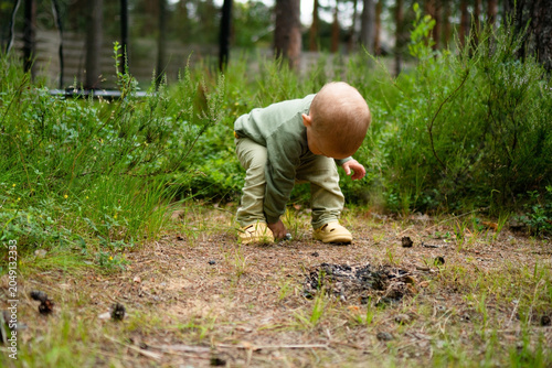 Photos Curious toddler crouching on forest floor exploring vegetation with absorbed interest