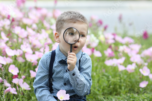 Canvas Print A charming close-up of a young boy in a blue shirt and suspenders, looking throu