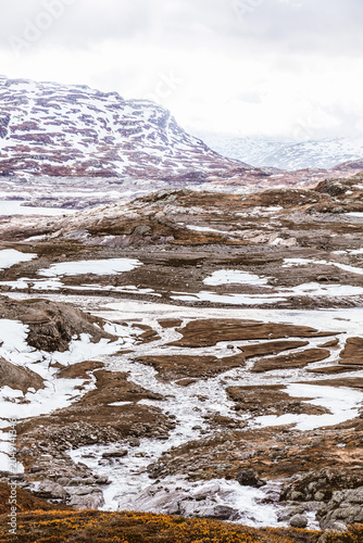 Bild auf Leinwand Remote mountain wilderness with lingering snow patches, highland terrain and dramatic cloud cover across Haukeli plateau in southern Norway