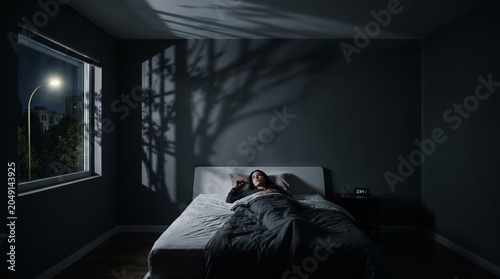 Woman lying in bed in a dark bedroom during the night