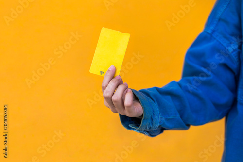 Young woman holding yellow card on colorful background