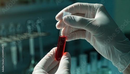 Scientific researcher in protective blue gloves holding a glass test tube filled with bright red blood for clinical analysis in a modern laboratory, medical diagnostics, photorealistic render.