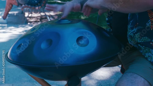 Musician's hands playing a handpan, a melodic percussion instrument creating a relaxing sound