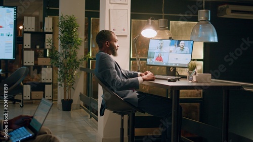 Foto African american employee in office holding team teleconference meeting with colleagues working from home