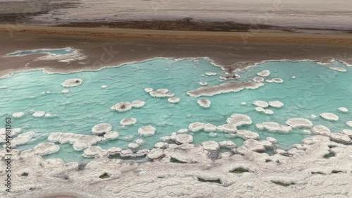 Cinematic orbital drone footage of the striking turquoise salt pools and white mineral formations known as Los Amargos near Guerrero Negro, Baja California Sur, Mexico. The aerial perspective highli-1