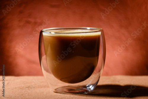 Close-up of a glass cup with coffee and milk.