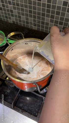 Coconut milk liquid is poured into the bowl of chocolate cake mixture