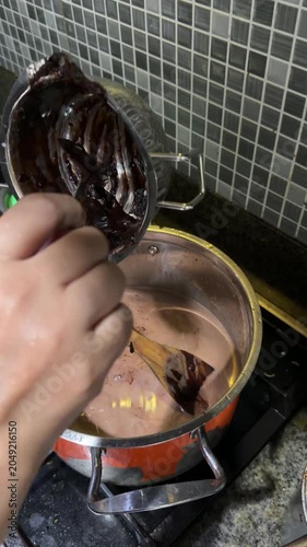 hands pouring chocolate liquid into the cake batter pan